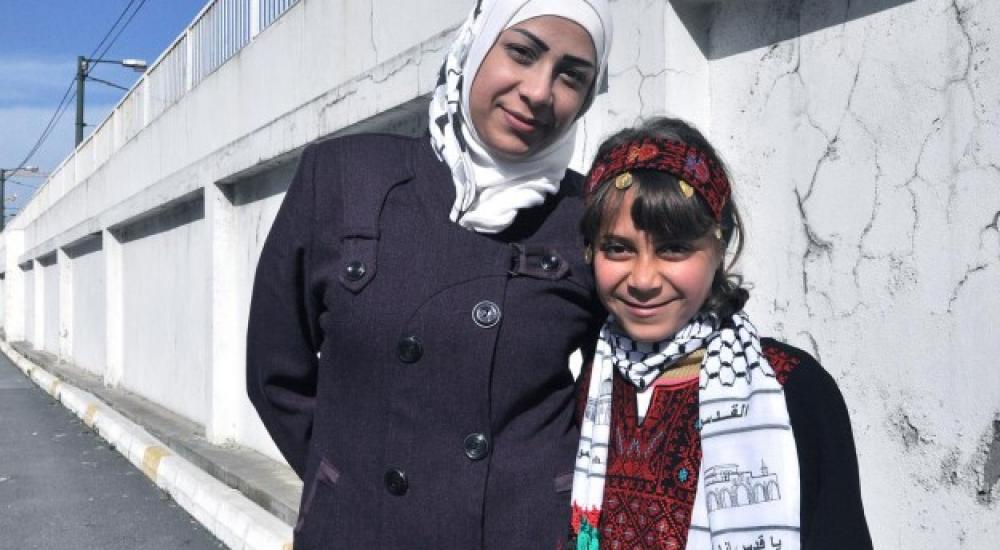 الطفلة سندس تقف إلى جانب أمها