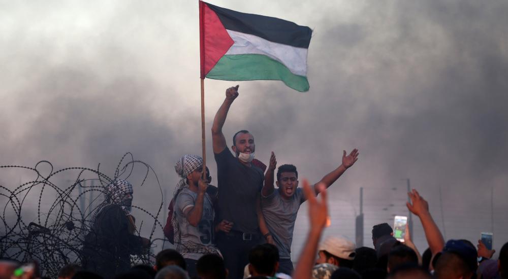800424-الفلسطينيون-يرفعون-شعارات-خلال-احتجاجاتهم-على-السياج-الحدودى