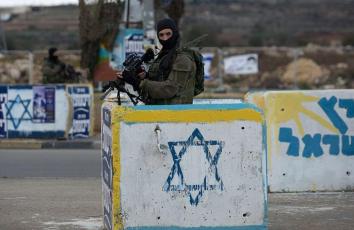 جندي إسرائيلي يقف خلف مكعب إسمنتي خوفًا من عمليات الدهس (أرشيف)