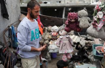 مواطن يبحث من بين الأنقاض عن جثث 18 من أقاربه تحت أنقاض منزلهم المدمر في مخيم البريج ويتمكن من استخراج دمى أطفاله