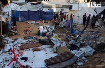 مواطنون يتفقدون آثار الدمار جراء قصف إسرائيلي على خيمة في شارع النصر غرب مدينة غزة