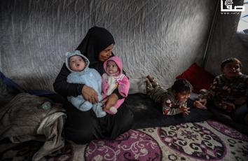 سيدة تعتني بطفليها أحدهما يعاني من ثقب في القلب في خيمة مهترئة في أجواء منخفض جوي حاد بمدينة غزة