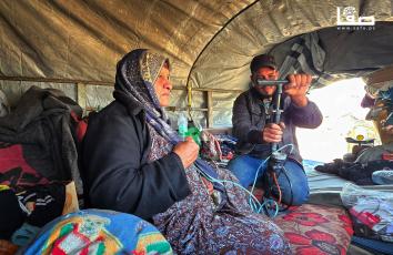 شاب يستخدم منفاخًا يدويًا لمساعدة والدته على التنفس في خانيونس